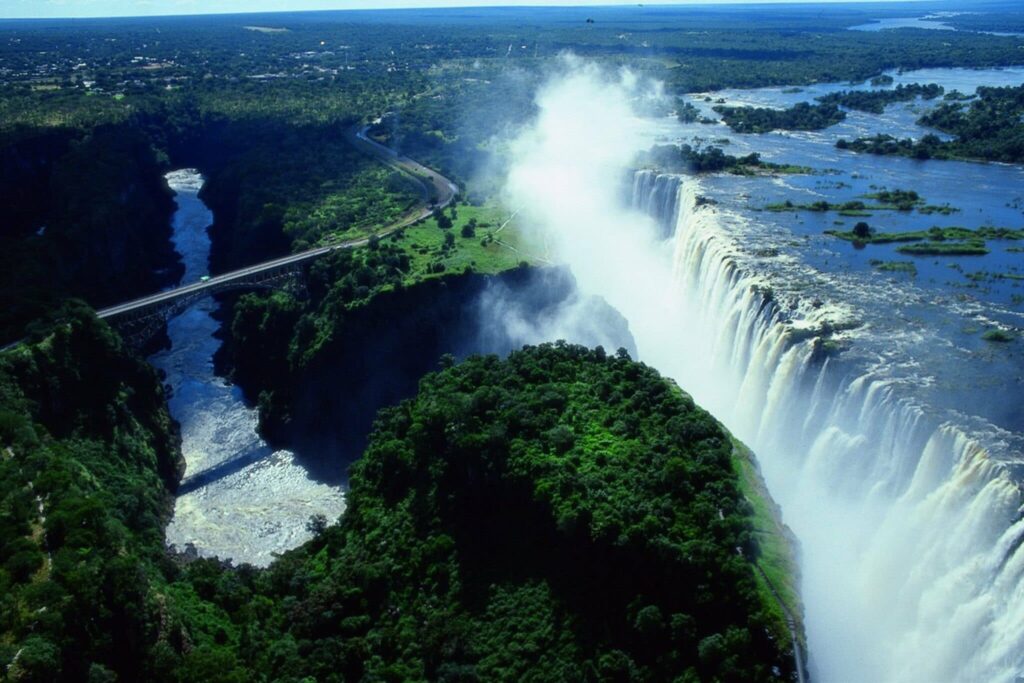 A breathtaking aerial view of Victoria Falls, Zimbabwe, showcasing the majestic waterfall surrounded by lush greenery.