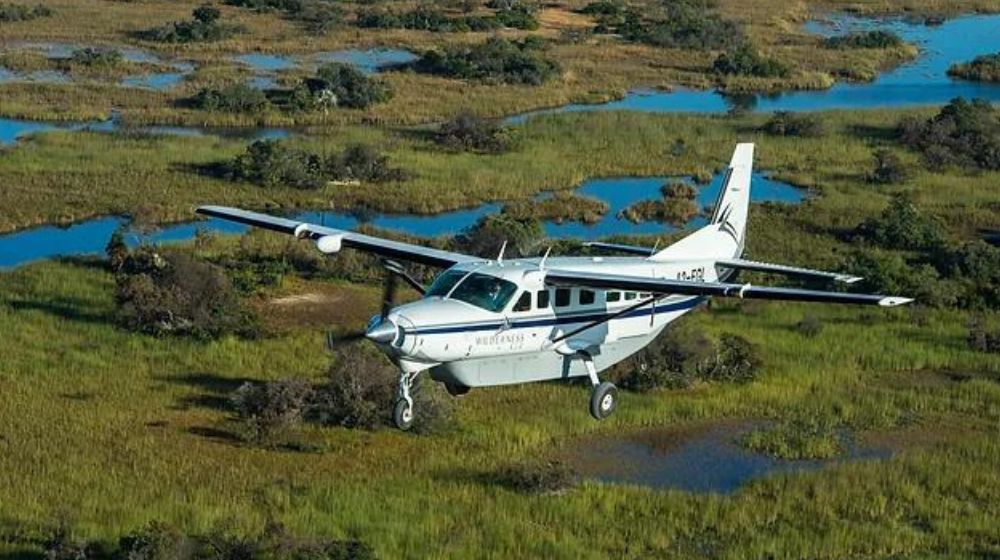 Maun: A stunning aerial view of the Okavango Delta with a light aircraft cruising above, highlighting the unique landscape and exciting adventure opportunities in this Botswana destination.