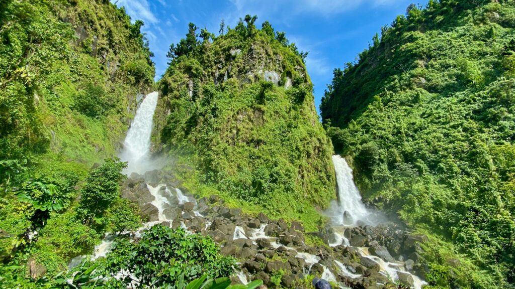Dominica - A stunning waterfall cascading down lush grass-covered mountains, showcasing the island's natural beauty.