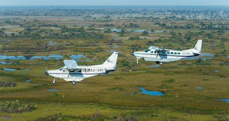 Maun: A breathtaking aerial view of the landscape with two light aircrafts flying over the vast wilderness, showcasing the beauty and adventure of this gateway to the Okavango Delta.