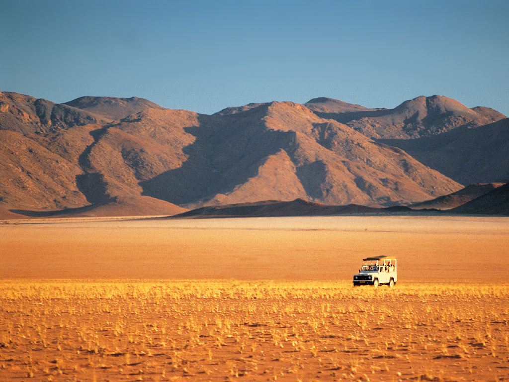 NamibRand Nature Reserve, Namibia - Scenic landscape with mountains and a 4x4 car, showcasing the adventure and beauty of the region.