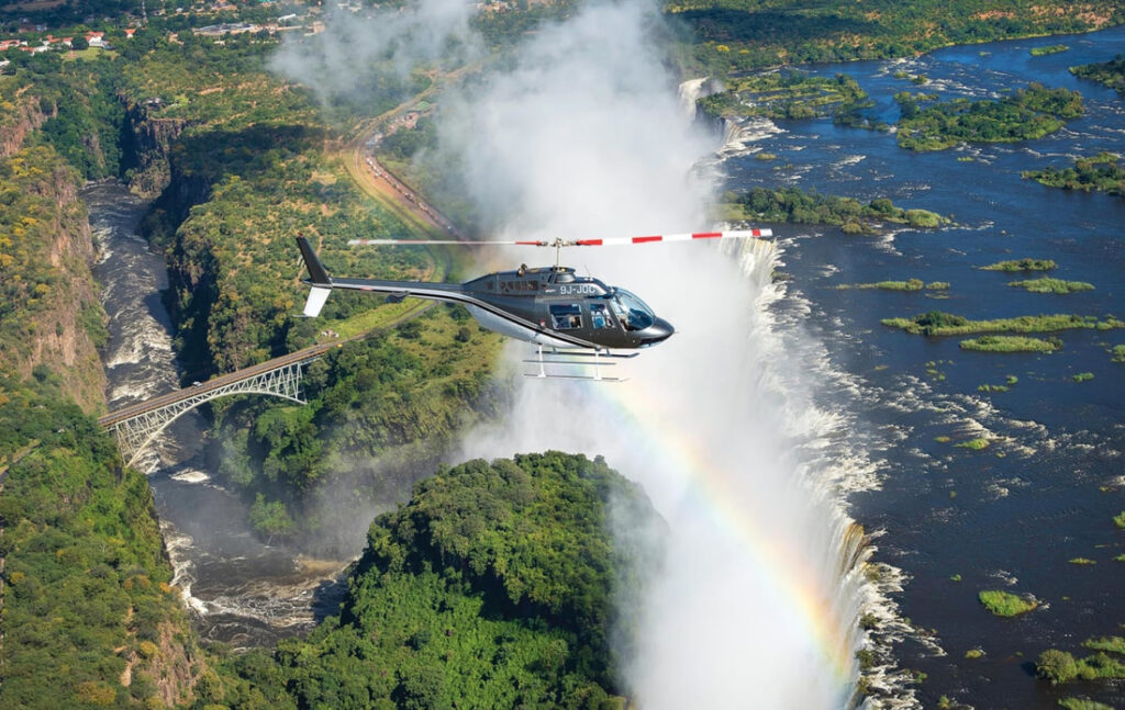 Aerial view of Victoria Falls, Zimbabwe, captured from a helicopter, showcasing the breathtaking waterfall and surrounding landscape.