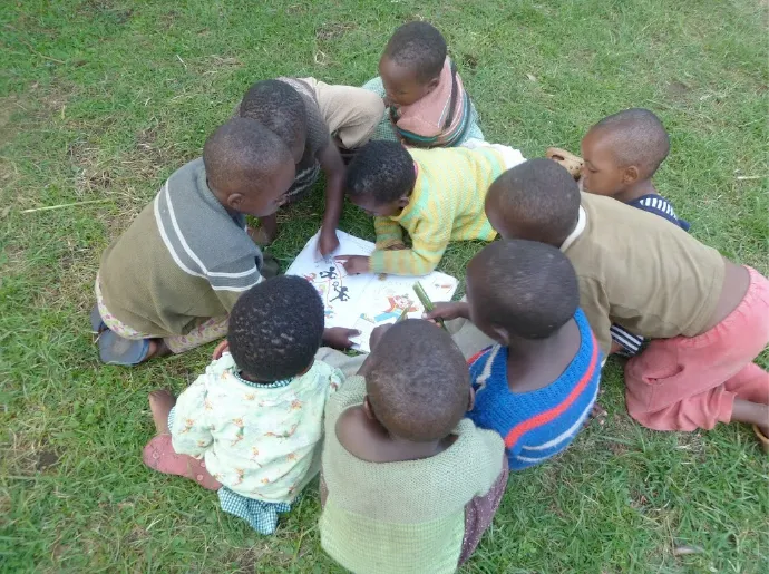 Children of Orphans in the Wild huddled together playing on the grass