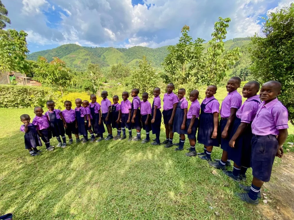 Children of Educate Bwindi proudly standing in their uniforms from smallest to biggest in a semi-circle