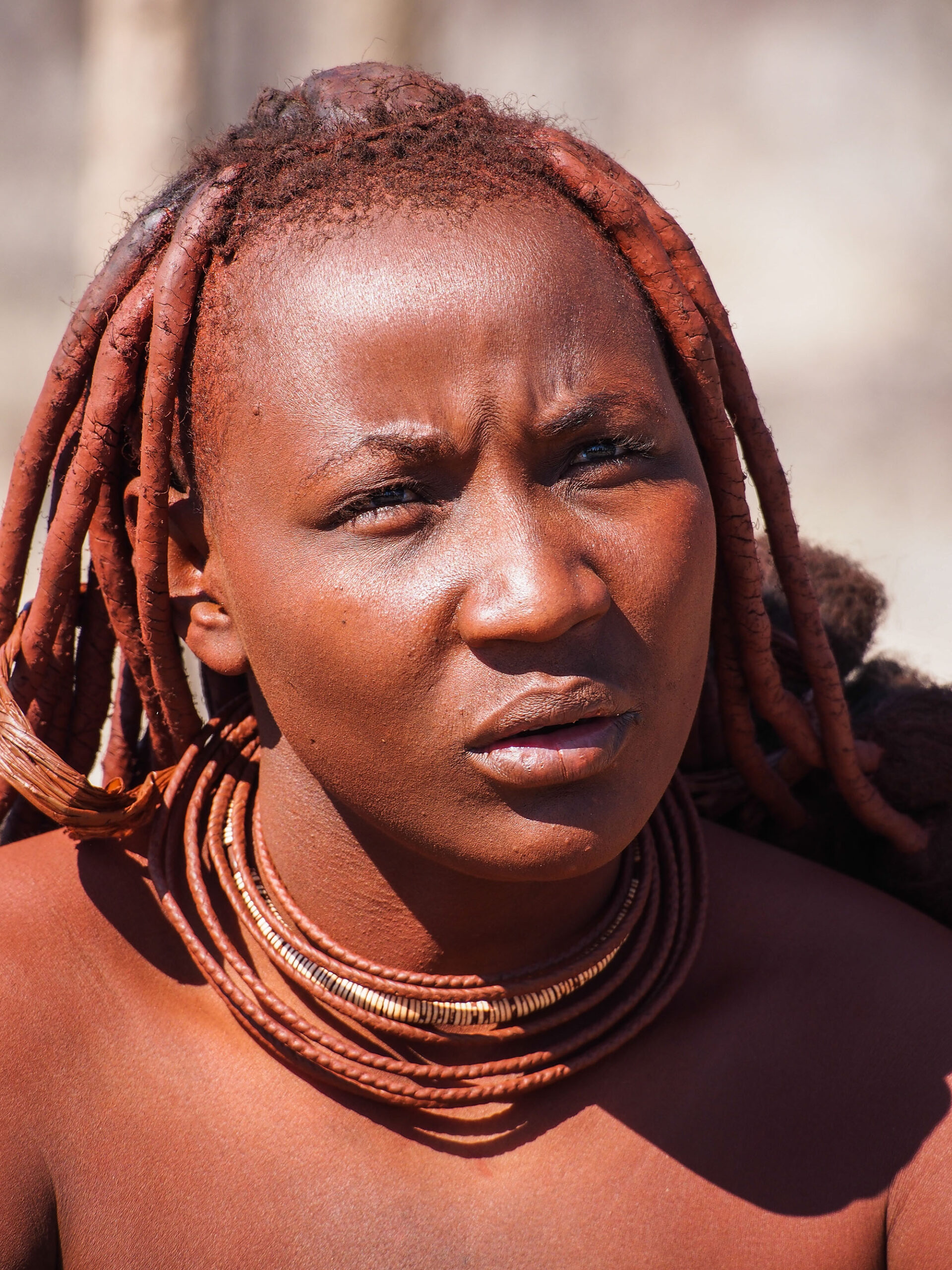 Close up of a Himba Lady's face, native to Kunene. Showing traditional neck wear and hair style.