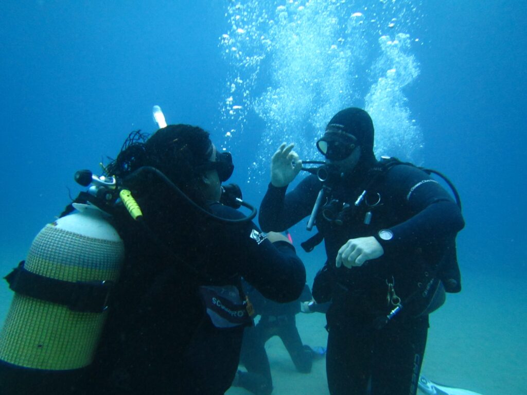 Dive Training Skills Practice, trainee demonstrating mestery of skills underwater with their instructor watching them.