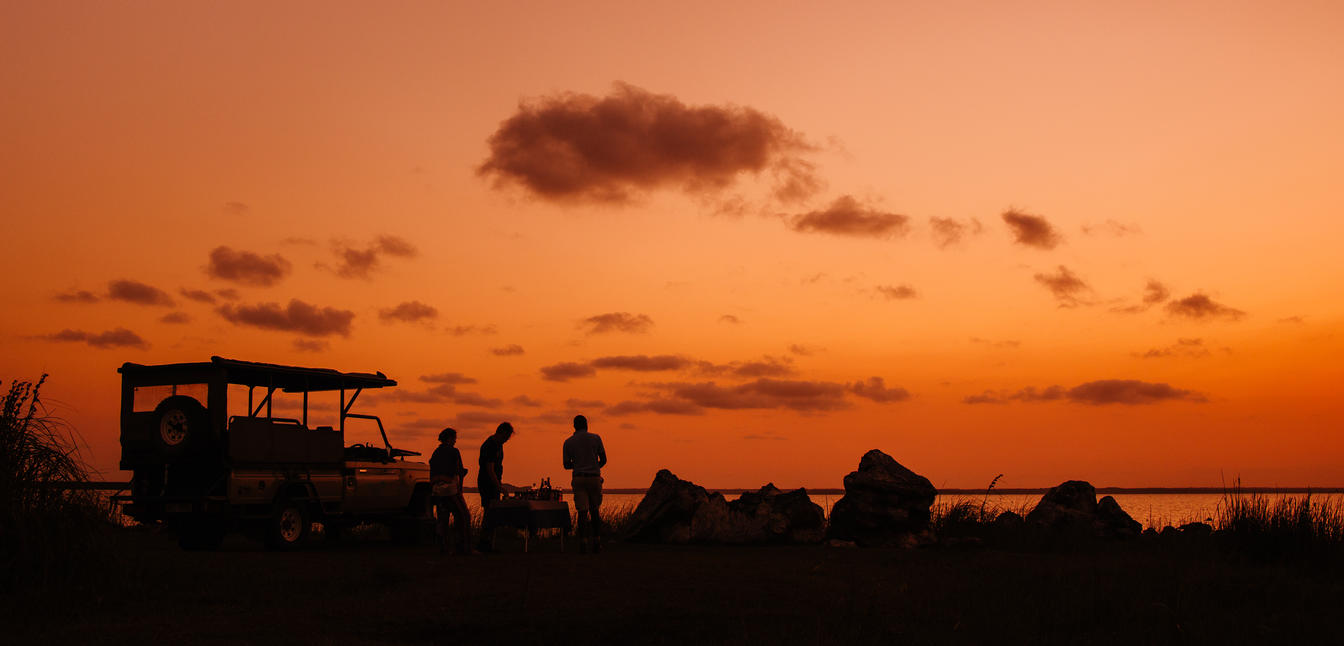 Sunset Safari with silhouettes of guests and the safari vehicle with the sunset as a backdrop