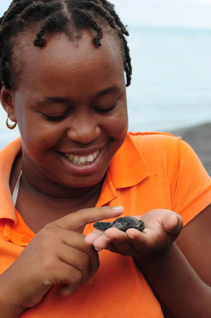 Oceans Forward Volunteer with a big smile on her face, holding a baby turtle under their care.