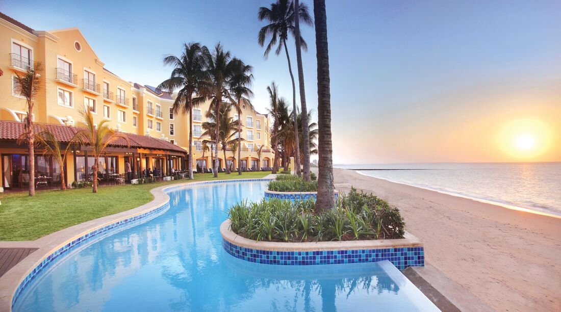 Swimming pool and sunrise with palms and Maputo Hotel Accommodation