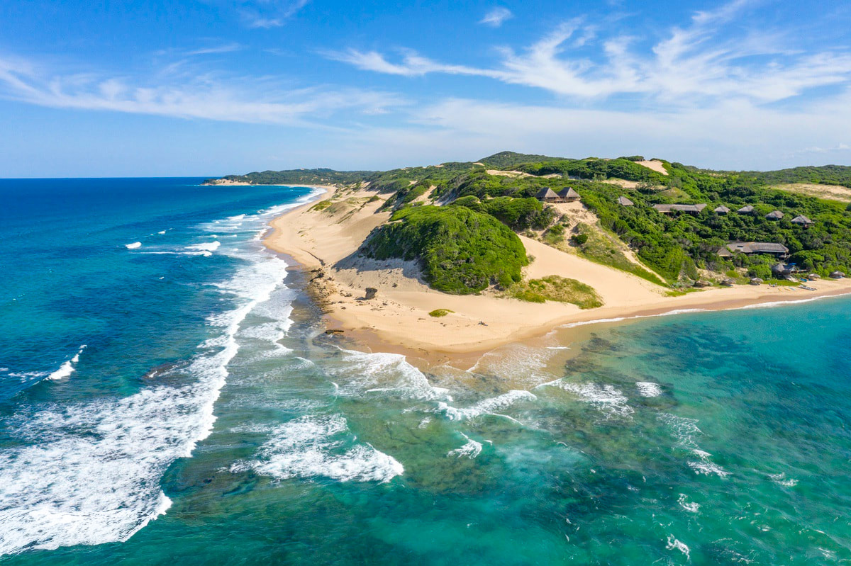 Aerial View of the point of Maputo, showing the tropical setting of land surrounded by the turquoise waters so clean you can see the reef below.