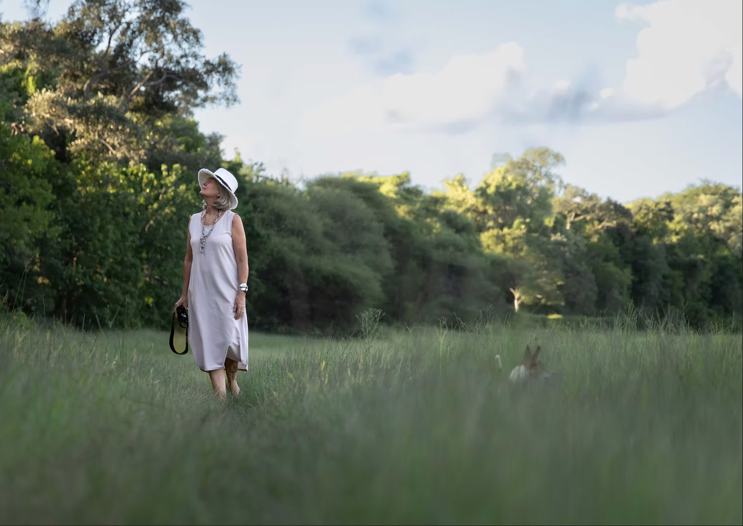 Morning walks in Maun next to the river. A lady enjoying the sky and a rabbit in the grass next to her.
