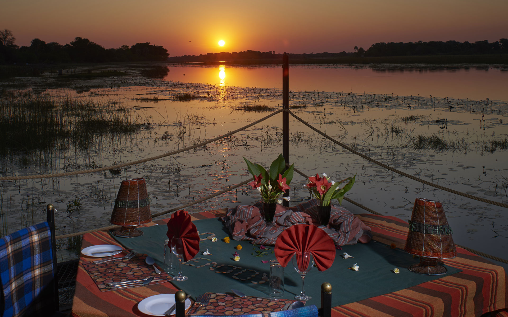Beautiful table set for dinner overlooking the river in Maun with a sunset as the back drop
