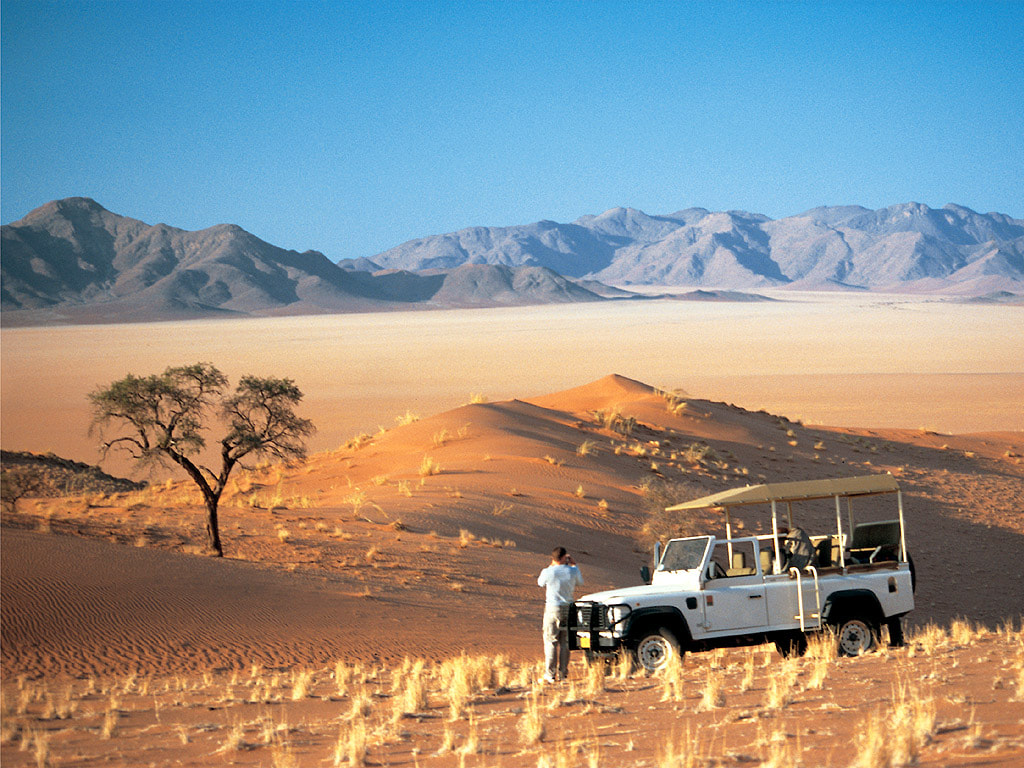 Guests in a 4 x 4 that have stopped to take photos of the NamibRand beauty that surrounds them.