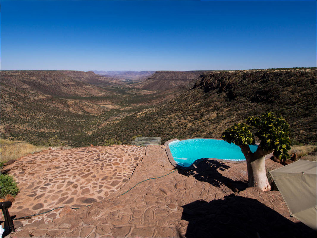 Swimming Pool with small tree to the left. Pool is on the cliff overlooking Damaraland valleys