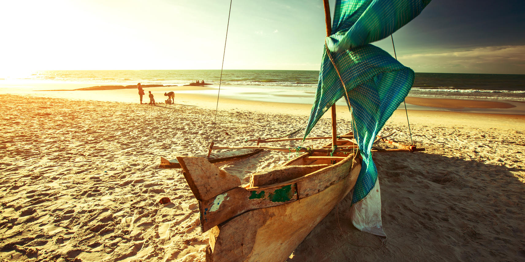Dhow on the beach with a family in the back ground making sand castles in Ponta Do Ouro